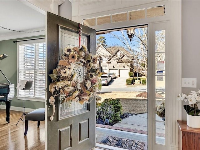 entrance foyer with ornamental molding, baseboards, and wood finished floors