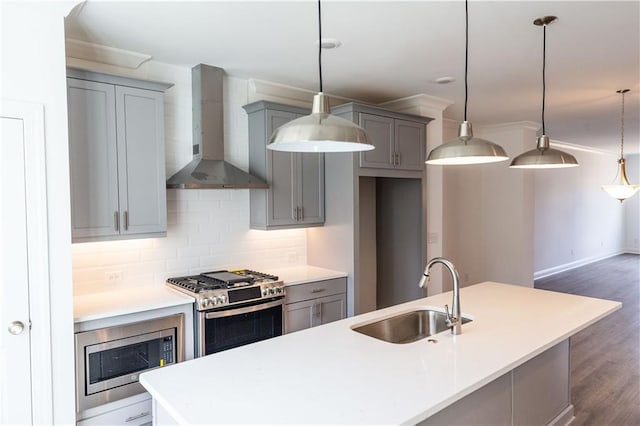 kitchen featuring sink, stainless steel appliances, tasteful backsplash, hanging light fixtures, and wall chimney range hood