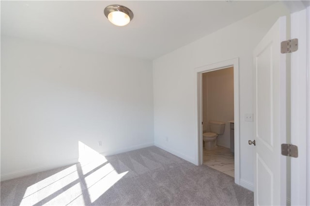 unfurnished bedroom featuring light colored carpet and connected bathroom