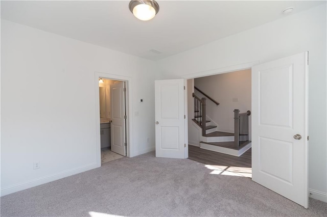 unfurnished bedroom with connected bathroom and light colored carpet