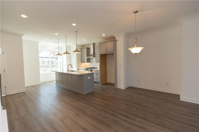 kitchen featuring sink, decorative light fixtures, wall chimney exhaust hood, dark hardwood / wood-style flooring, and a kitchen island with sink