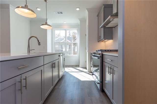 kitchen with wall chimney exhaust hood, decorative light fixtures, stainless steel gas stove, gray cabinetry, and sink