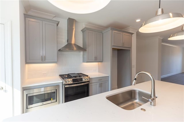 kitchen featuring wall chimney exhaust hood, pendant lighting, backsplash, appliances with stainless steel finishes, and sink