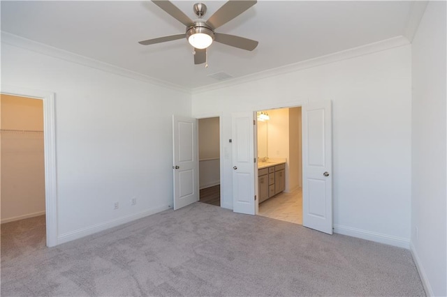 unfurnished bedroom featuring a spacious closet, a closet, light colored carpet, ornamental molding, and ceiling fan