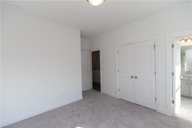 unfurnished bedroom featuring a closet, light carpet, and connected bathroom