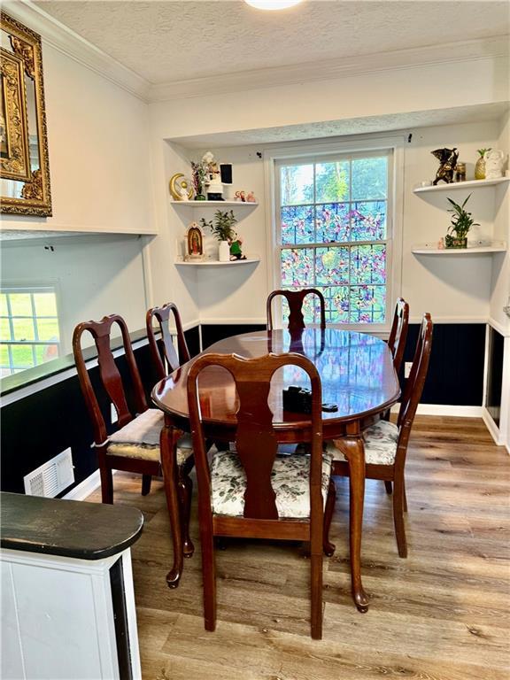 5347 Ocarol Ct, Stone Mountain, GA 30088 - dining area with light wood-style floors, a textured ceiling, and crown molding