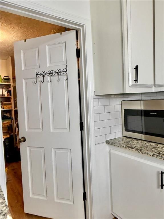 5347 Ocarol Ct, Stone Mountain, GA 30088 - kitchen view of stainless steel microwave, white cabinetry, and tasteful backsplash