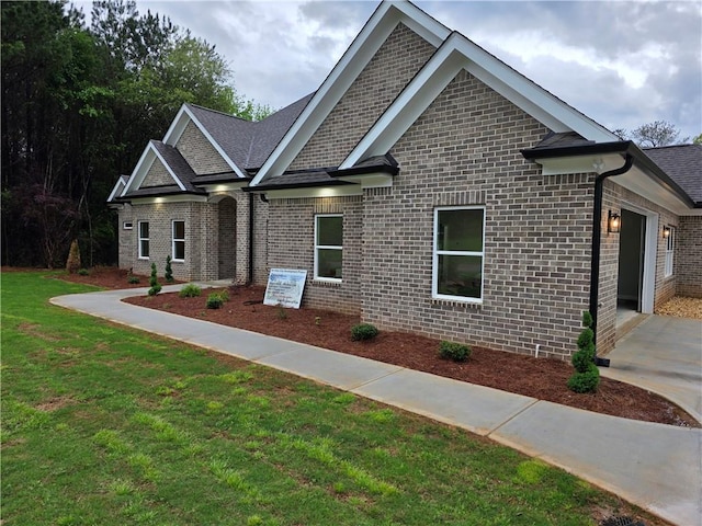 craftsman inspired home featuring a lawn and brick siding
