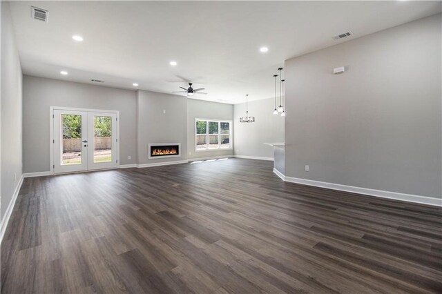unfurnished living room with baseboards, recessed lighting, dark wood finished floors, arched walkways, and ceiling fan with notable chandelier