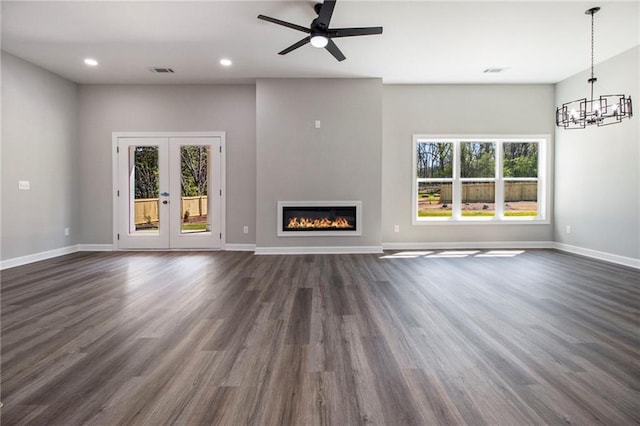 unfurnished dining area featuring a chandelier, baseboards, arched walkways, a towering ceiling, and dark wood-type flooring