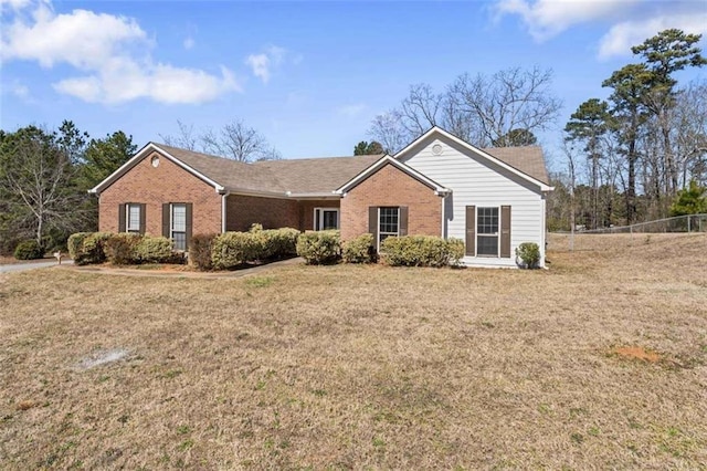 ranch-style home featuring brick siding, a front lawn, and fence