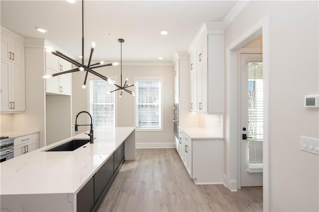 kitchen featuring sink, light stone counters, white cabinets, decorative light fixtures, and a chandelier