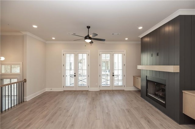 unfurnished living room featuring a fireplace, ornamental molding, light hardwood / wood-style floors, ceiling fan, and french doors