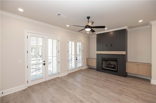 unfurnished living room featuring crown molding, a large fireplace, light hardwood / wood-style floors, and french doors