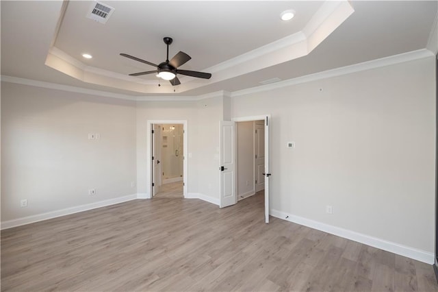 empty room with crown molding, ceiling fan, a raised ceiling, and light hardwood / wood-style flooring