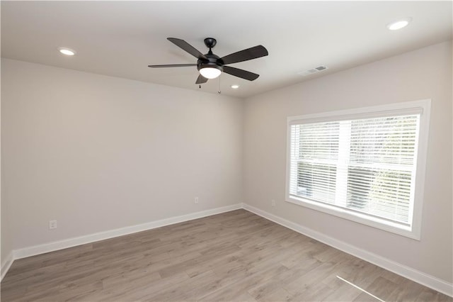 empty room with ceiling fan and light hardwood / wood-style flooring