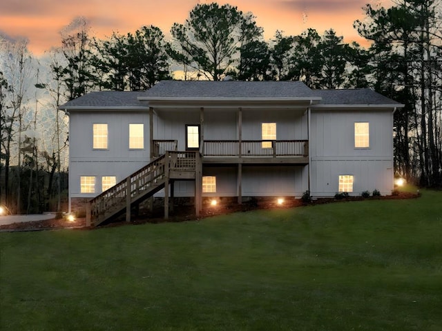 back house at dusk featuring a lawn