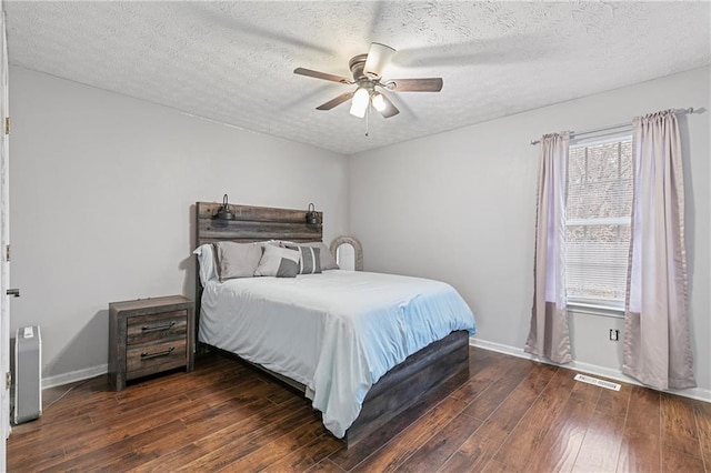 bedroom with dark wood-type flooring, a textured ceiling, multiple windows, and ceiling fan