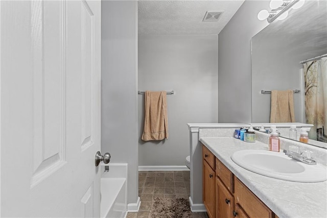 bathroom with toilet, a textured ceiling, and vanity