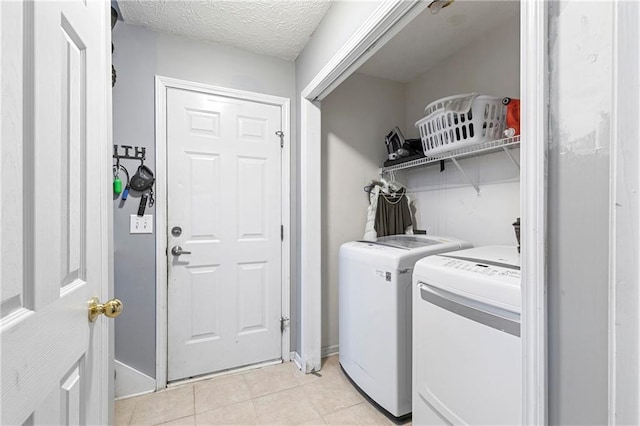 washroom featuring light tile patterned flooring, a textured ceiling, and washing machine and clothes dryer