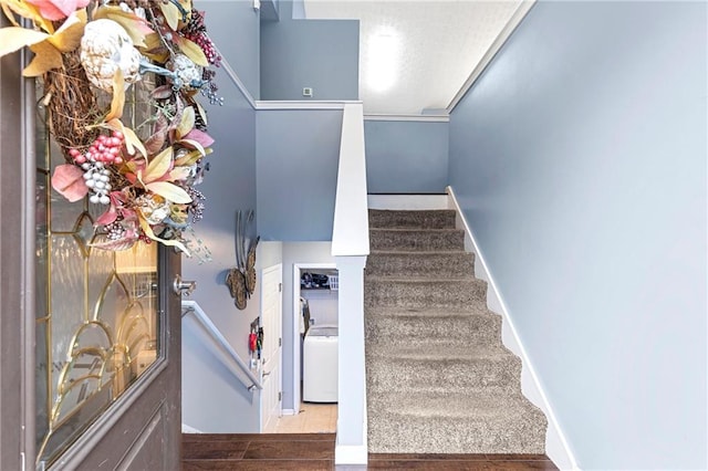 stairway featuring ornamental molding and washer / dryer