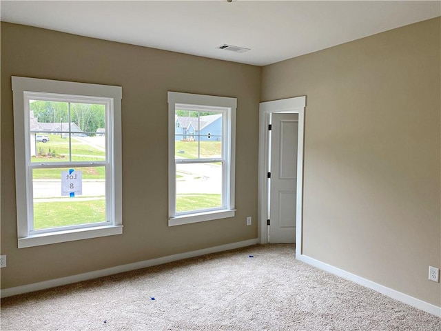 carpeted empty room with baseboards, a wealth of natural light, and visible vents