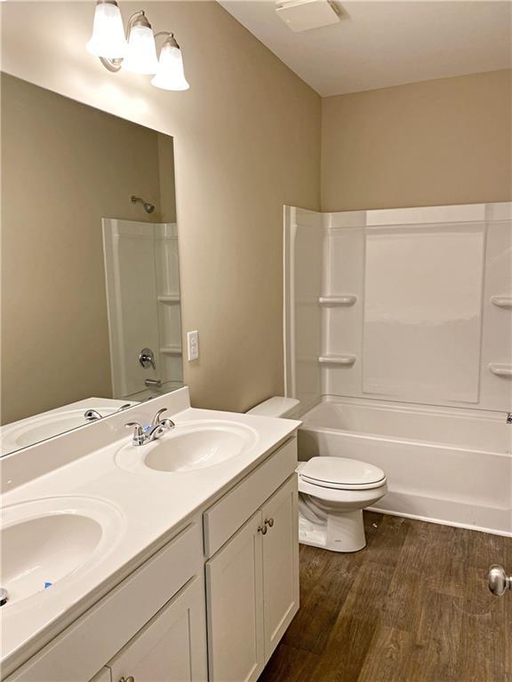 full bath with a sink, toilet, and wood finished floors