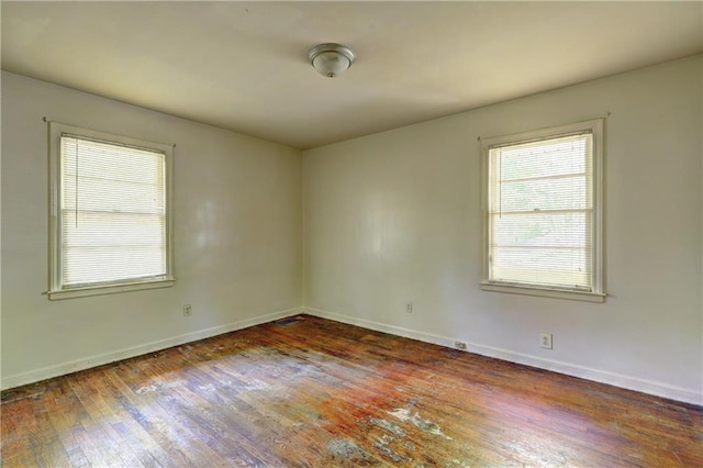 unfurnished room featuring plenty of natural light, baseboards, and hardwood / wood-style flooring