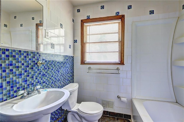 bathroom with tile walls, toilet, visible vents, a sink, and tile patterned floors