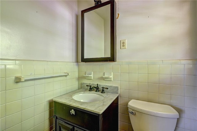 bathroom with tile walls, toilet, wainscoting, and vanity