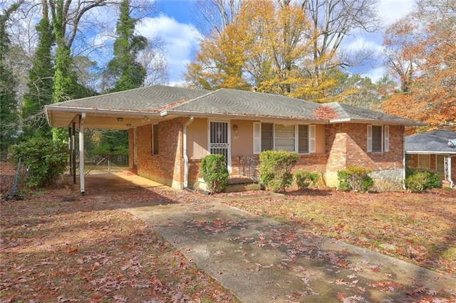 single story home with driveway, brick siding, covered porch, and a carport