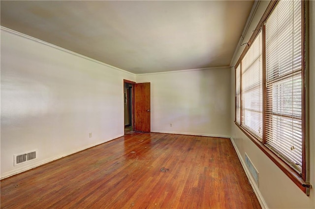 spare room featuring crown molding, visible vents, and wood finished floors