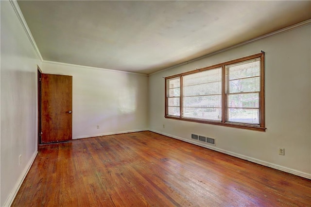 unfurnished room with crown molding, visible vents, wood finished floors, and baseboards