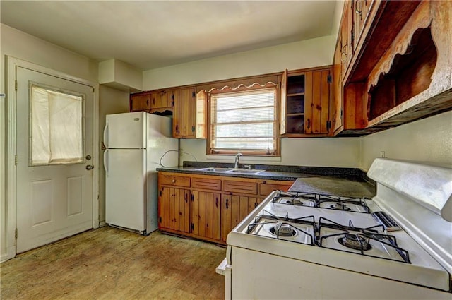 kitchen featuring brown cabinets, light wood-style flooring, a sink, and white appliances