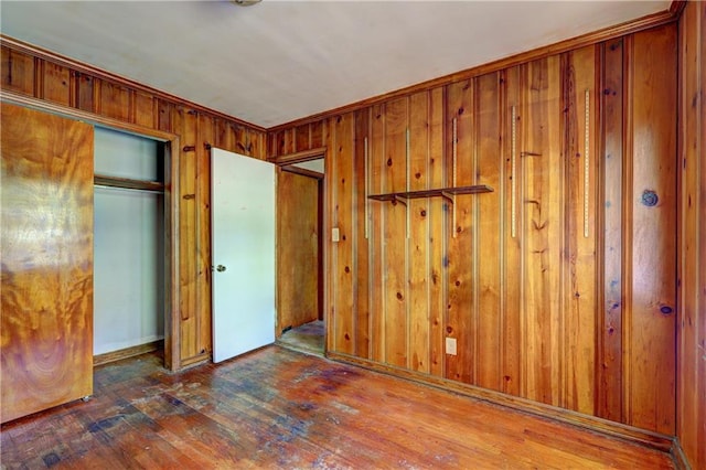 unfurnished bedroom featuring a closet, wood walls, and wood-type flooring