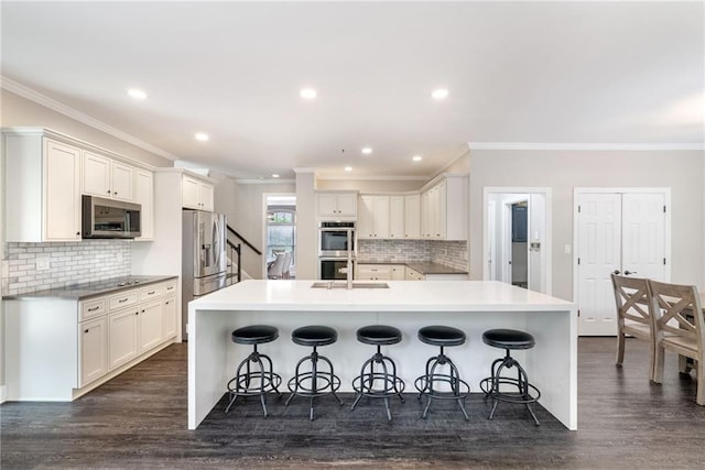 5041 Corinault Pl NW, Acworth, GA 30101 - kitchen with stainless steel appliances, crown molding, tasteful backsplash, a breakfast bar, and dark wood finished floors