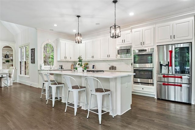 882 Hallbrook Ln, Milton, GA 30004 - kitchen featuring stainless steel appliances, light countertops, white cabinetry, a kitchen island, and backsplash
