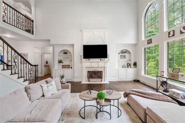 882 Hallbrook Ln, Milton, GA 30004 - living room featuring a towering ceiling, built in shelves, a fireplace with flush hearth, stairway, and wood finished floors