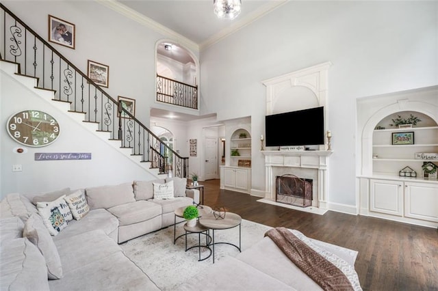 882 Hallbrook Ln, Milton, GA 30004 - living room with crown molding, built in shelves, a towering ceiling, stairway, and dark wood finished floors