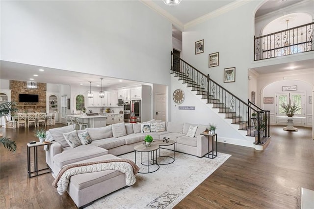 882 Hallbrook Ln, Milton, GA 30004 - living room featuring a towering ceiling, arched walkways, dark wood-type flooring, crown molding, and stairs