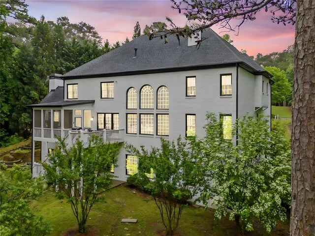 882 Hallbrook Ln, Milton, GA 30004 - back of property at dusk with stucco siding, roof with shingles, and a sunroom