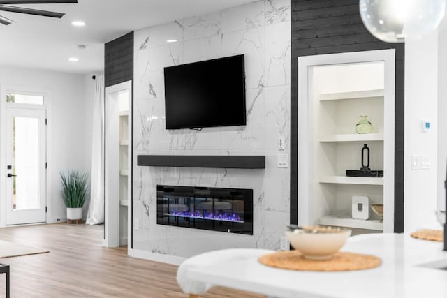 living room with a premium fireplace, light hardwood / wood-style flooring, and built in shelves