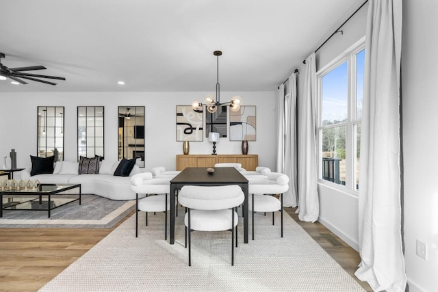 dining room featuring ceiling fan with notable chandelier and wood-type flooring