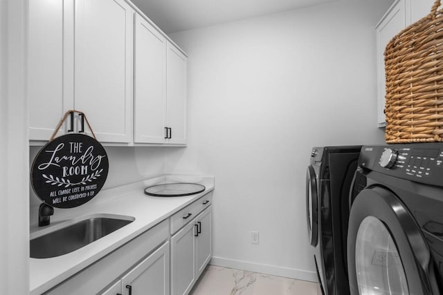 clothes washing area with cabinets, washing machine and clothes dryer, and sink