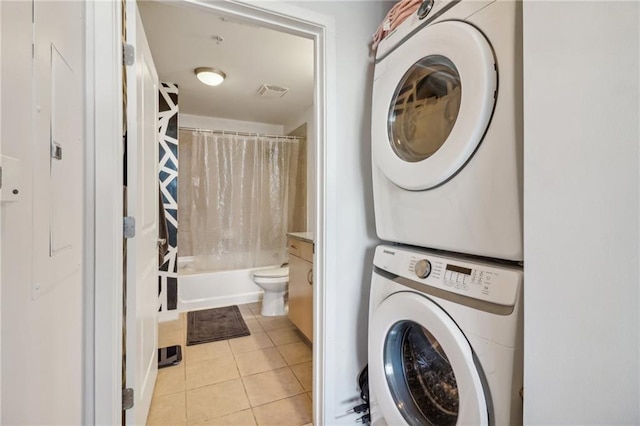 washroom featuring stacked washer / drying machine and light tile patterned flooring