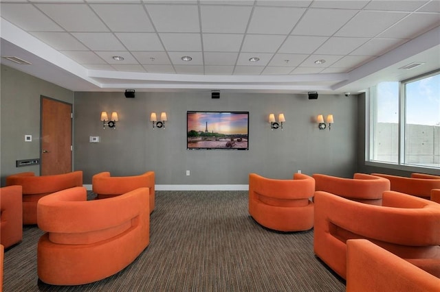 carpeted home theater room with a drop ceiling and a tray ceiling