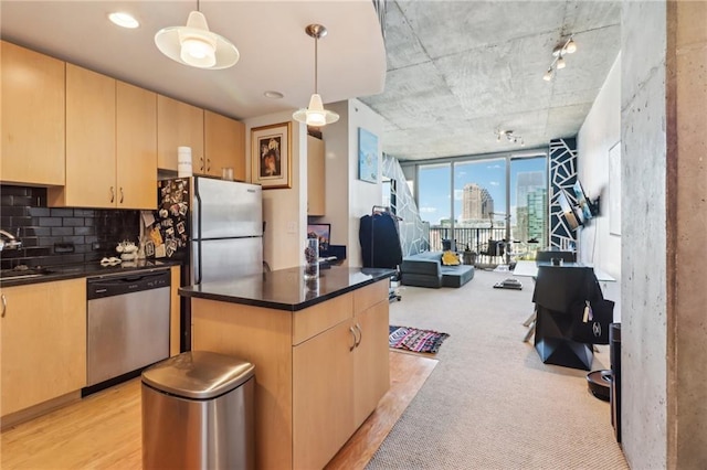 kitchen with appliances with stainless steel finishes, sink, light wood-type flooring, pendant lighting, and light brown cabinets