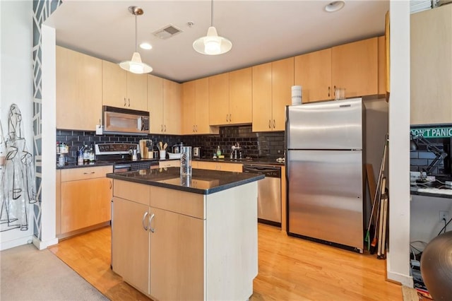 kitchen featuring a kitchen island, hanging light fixtures, stainless steel appliances, light wood-type flooring, and light brown cabinetry