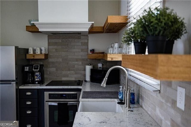 kitchen with a sink, decorative backsplash, appliances with stainless steel finishes, custom exhaust hood, and dark cabinets