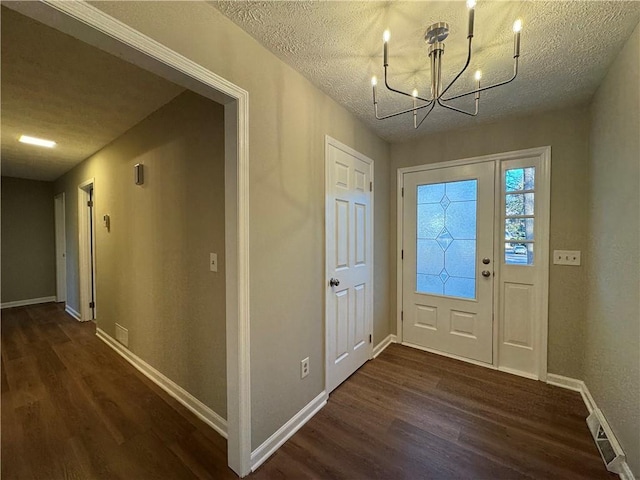 foyer entrance featuring an inviting chandelier, dark hardwood / wood-style flooring, and a textured ceiling